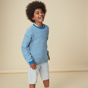 A boy wearing a striped t-shirt and white shorts from Tommy Hilfiger Kids