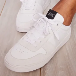 A man's feet wearing white TOMS sneakers