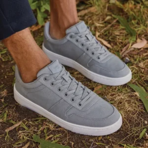 A man's feet wearing grey TOMS sneakers