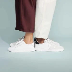 feet of a man and woman wearing white TOMS sneakers